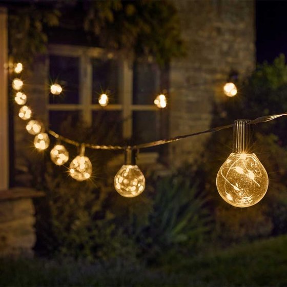 String of decorative outdoor lights hanging in a garden setting.